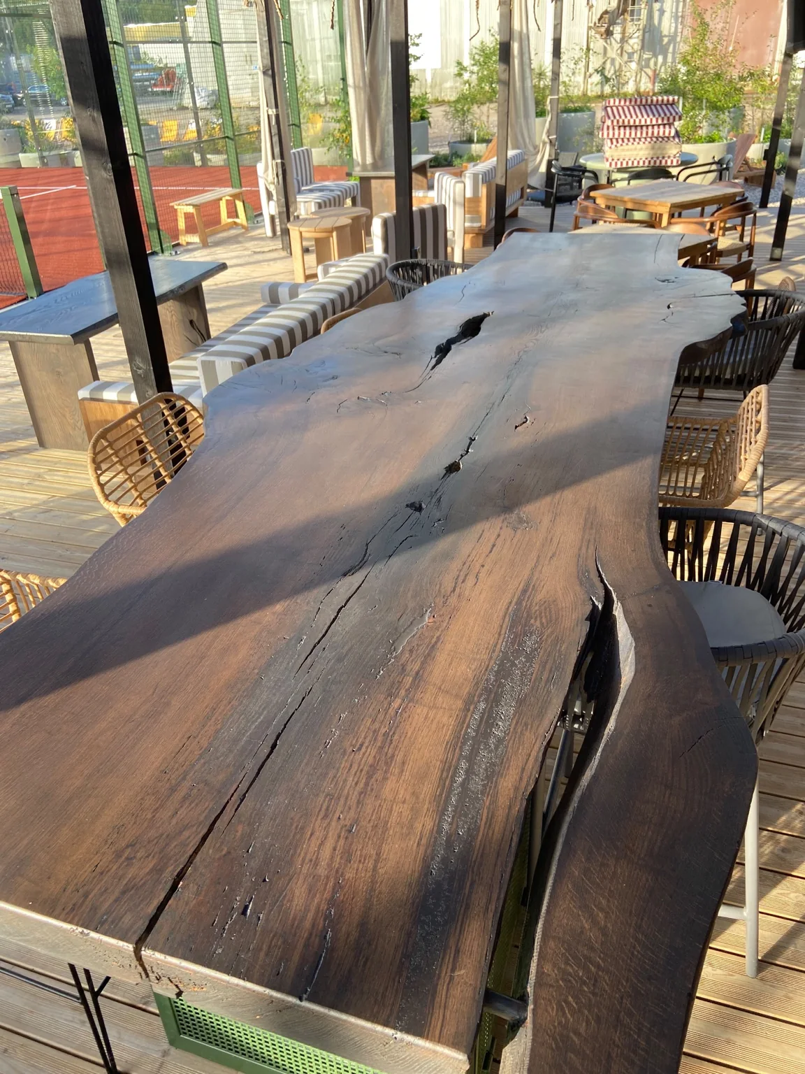 Long dark natural-edge bar table with open timber features on green bases — Photograph 2