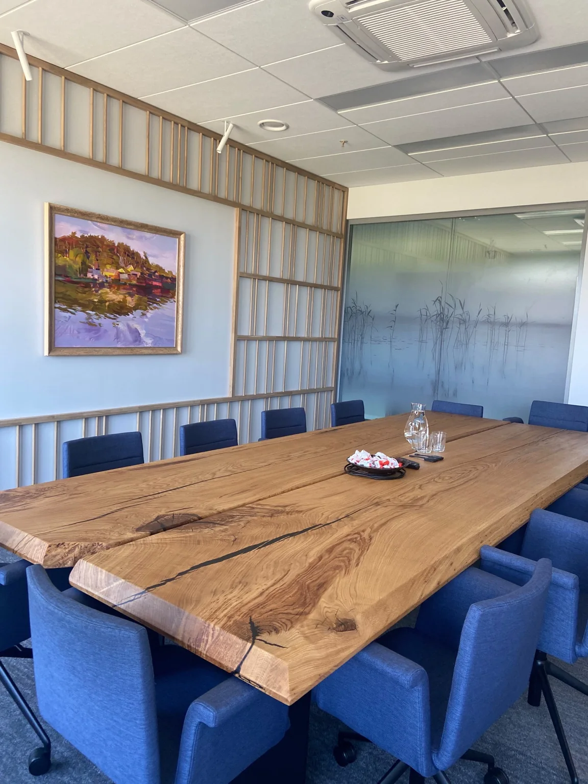 Large wooden meeting table with natural edges surrounded by blue chairs