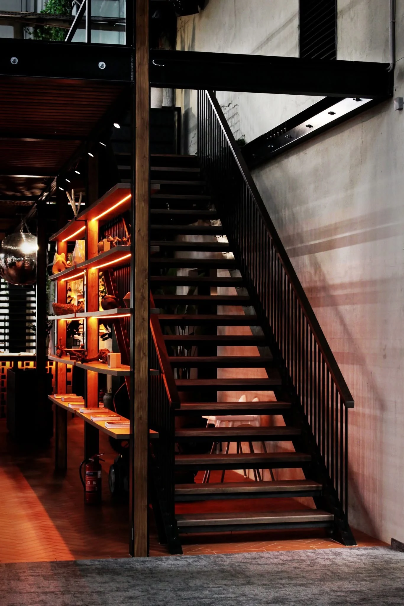 Wooden staircase beside illuminated shelving in the same interior