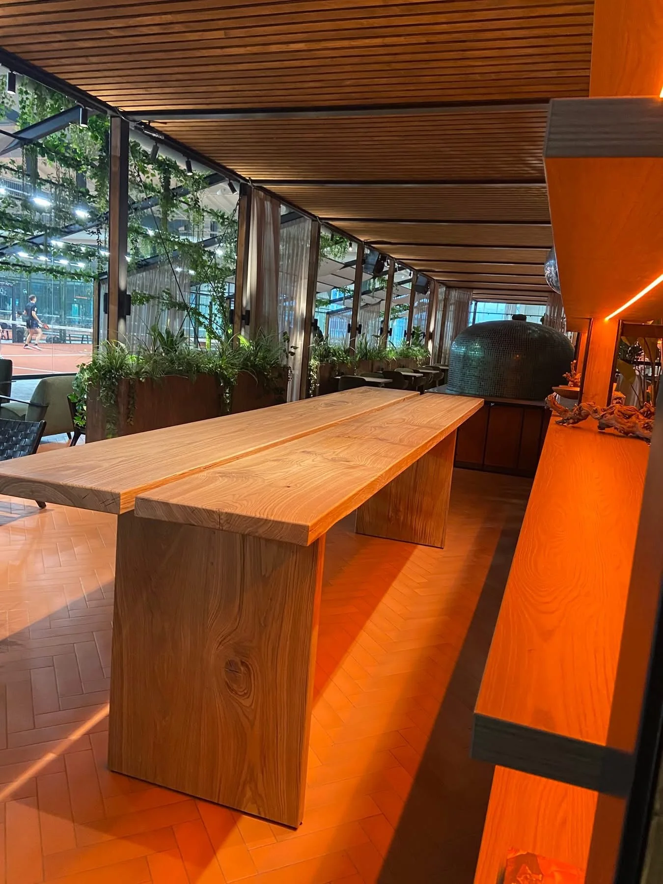 Long two-section wooden table with wooden panel legs in a warm interior — Photograph 2