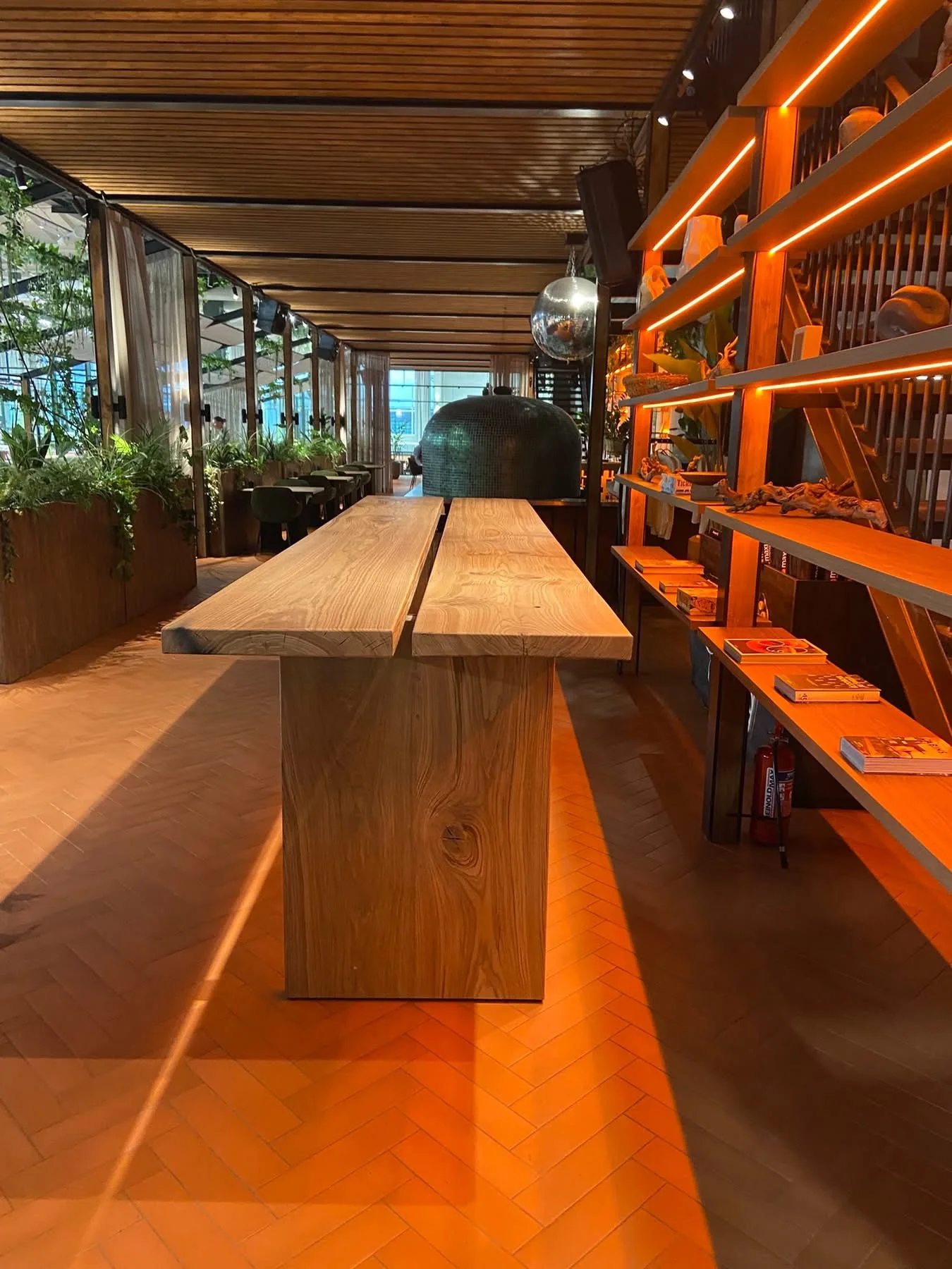 Long two-section wooden table with wooden panel legs in a warm interior — Photograph 3