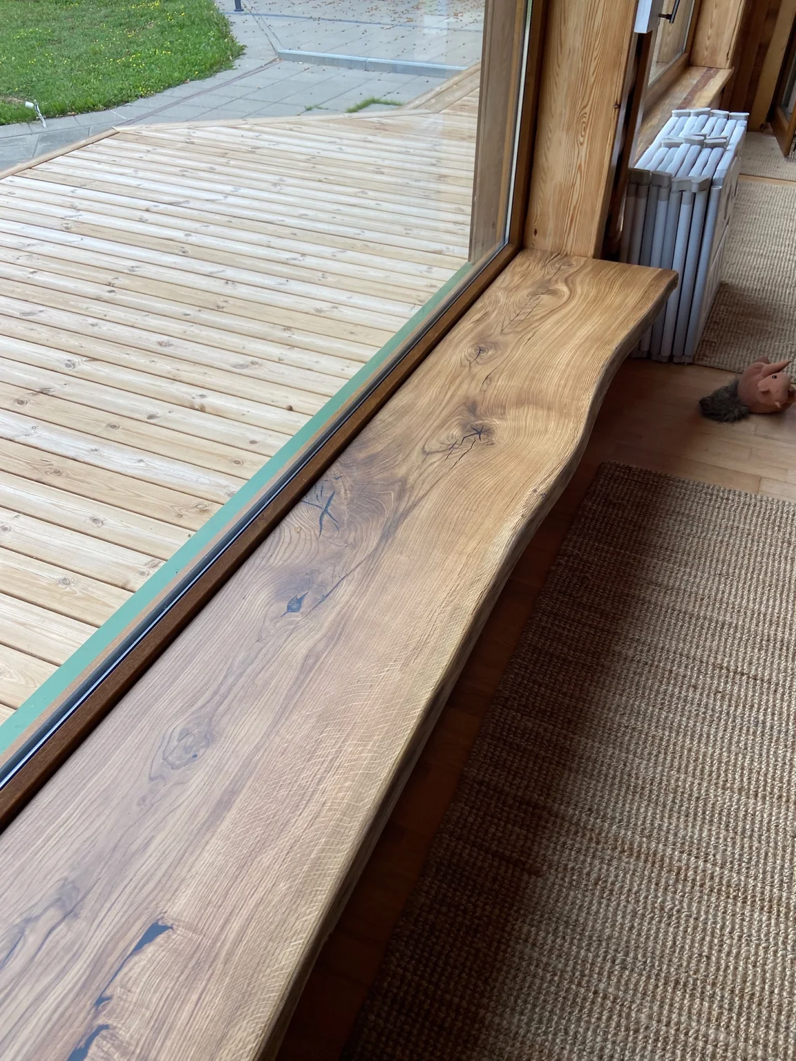 Broad natural-edge wooden windowsill in a timber interior